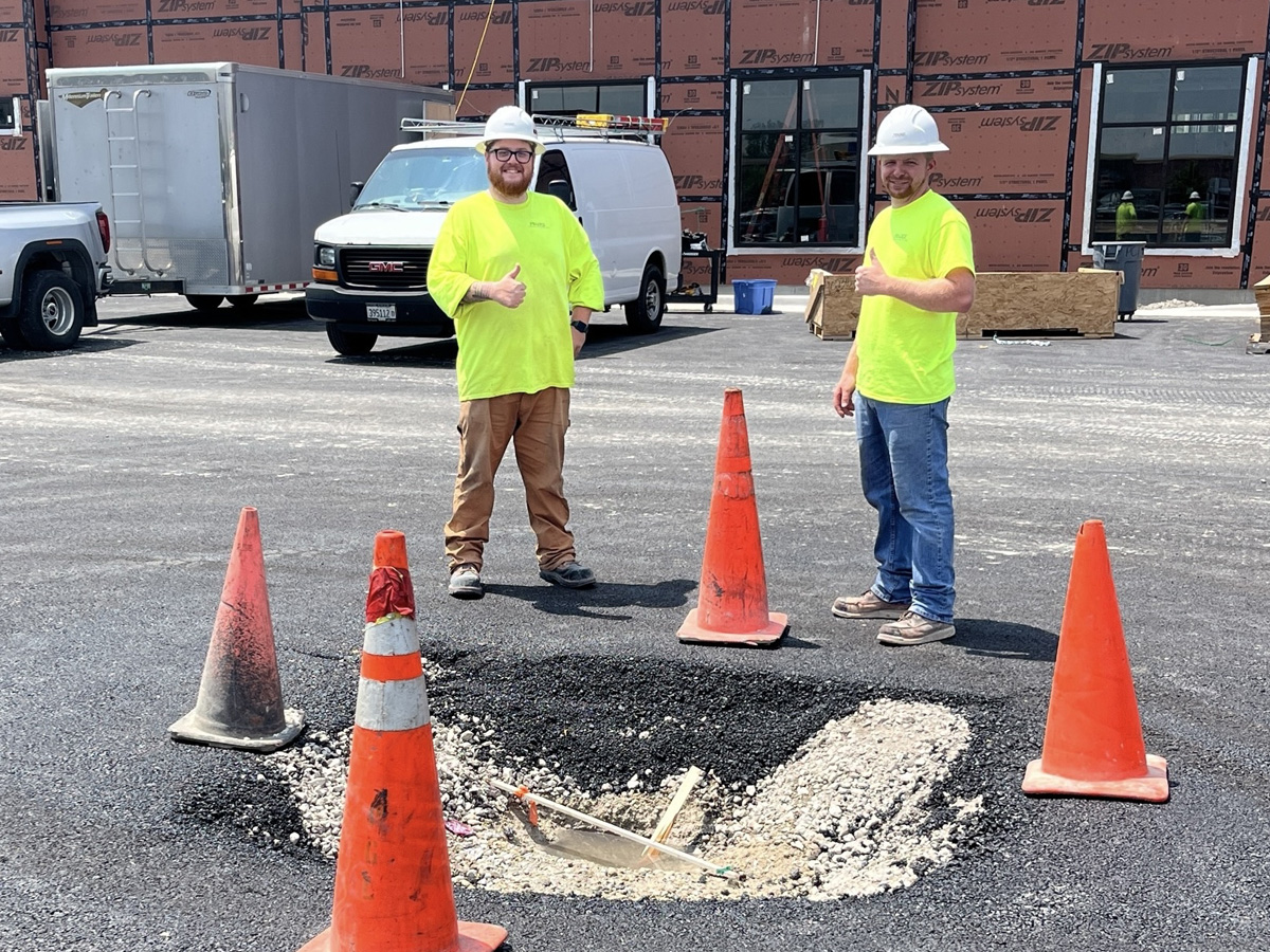 Prairie Contractors employees in front sink hole with caution cones